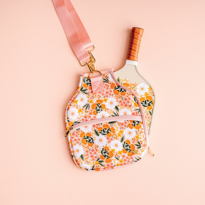 The Darling Effectβs Sweet Meadow Pickleball Case and matching strap, shown on a light pink background with a white paddle, offer an elegant way to protect and carry your pickleball paddles.