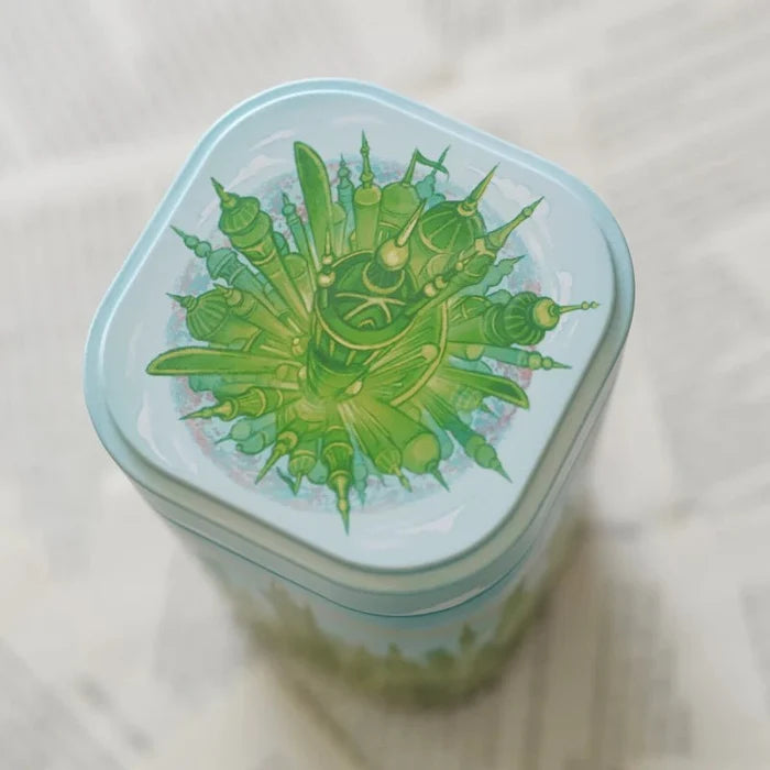 Emerald City Fairytale Tin Village lid top-down view — light blue mint tin with detailed green fantasy cityscape illustration featuring spires and towers, from LitJoy Winter Romantasy TBR Box