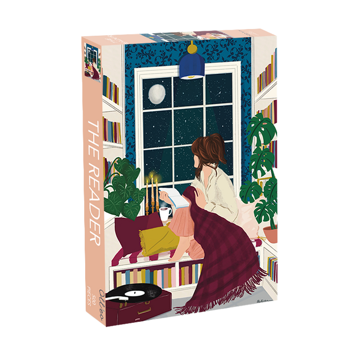 The Reader by Olleo Puzzles is a 500 piece jigsaw showing a woman reading by a window at night, with her cat, bookshelves, plants, and record player. The completed puzzle measures 18.9" x 13.4".