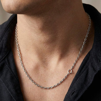 Close-up of a male model wearing a thin 2mm sterling silver anchor link necklace chain styled with a dark open-collar shirt.