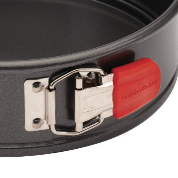 Close-up of the 9-Inch Nonstick Springform Pan in black, featuring a red latch for effortless food release.