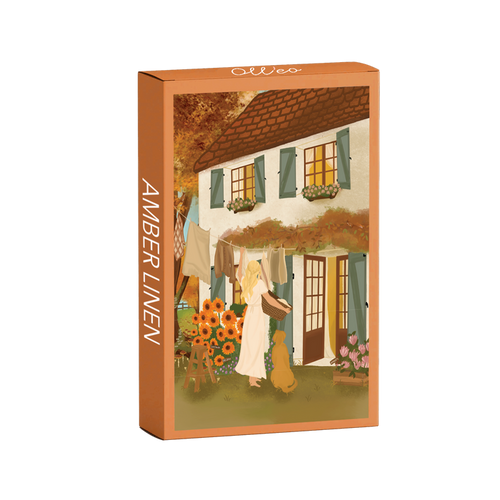 The Amber Linen | 99 Piece Jigsaw Puzzle by Olleo Puzzles features Nicolet Boon's artwork of a woman with a dog hanging laundry outside a flower-adorned cottage with green shutters.