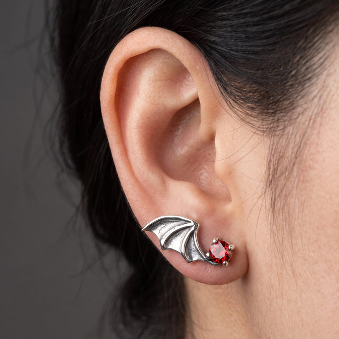 Worn on the earlobe, the sterling bat wing sweeps back across the lobe with the red stone forward