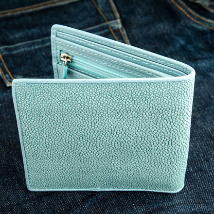 Zipper and pull sit along the pebbled turquoise hide, the interior compartments just showing inside.