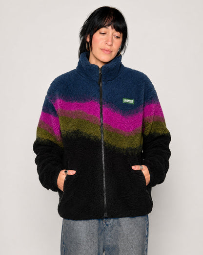 A woman wearing a fuzzy quarter-zip fleece jacket with horizontal wavy stripes in navy blue, magenta, olive green, and black, paired with light-wash jeans against a plain light gray background.

Shop Borealis High Pile Fleece Jacket Inspired by Alaskan Parks | multi-color