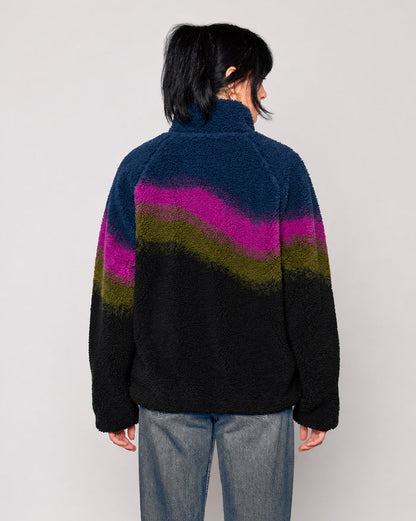 A person viewed from the back wearing a fuzzy quarter-zip fleece jacket with a wavy color-block pattern in navy, magenta, olive green, and black, paired with blue jeans against a light gray studio background.

Shop Borealis High Pile Fleece Jacket Inspired by Alaskan Parks | multi-color