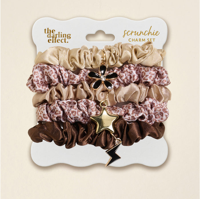 The Darling Effect's Born Wild Scrunchie Charm Set features leopard, gold, and brown scrunchies adorned with flower, star, and lightning bolt hair charms for a chic accessory upgrade.