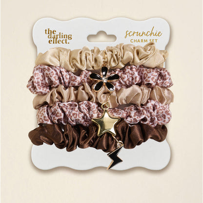 The Darling Effect's Born Wild Scrunchie Charm Set features leopard, gold, and brown scrunchies adorned with flower, star, and lightning bolt hair charms for a chic accessory upgrade.