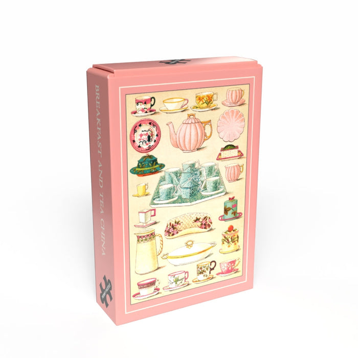 A pink rectangular box from Penny Puzzle, featuring vintage breakfast and tea china illustrations and "BREAKFAST TEA CHINA" on the side. Contains a charming 99 piece jigsaw puzzle for vintage lovers.