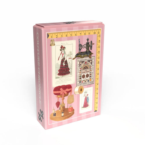 The "Couture Chronicles" 99-piece jigsaw puzzle by Penny Puzzle comes in a pink box with vintage dressmaking illustrations and a yellow measuring tape border, making it a charming collector's minipuzzle.