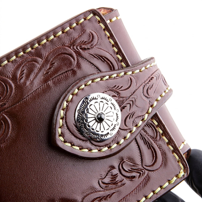 Macro of a 925 sterling silver concho set with a black onyx stone on a dark brown tooled leather wallet strap.