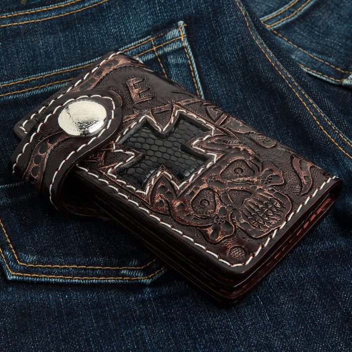 Dark brown cowhide wallet featuring a hand-tooled skull and cross design inlaid with black lizard leather on denim.