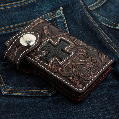 Dark brown cowhide wallet featuring a hand-tooled skull and cross design inlaid with black lizard leather on denim.
