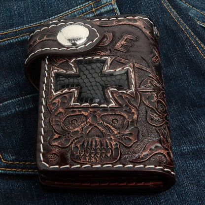 Close-up of the hand-tooled skull motif and white stitched border on the dark brown cowhide wallet.