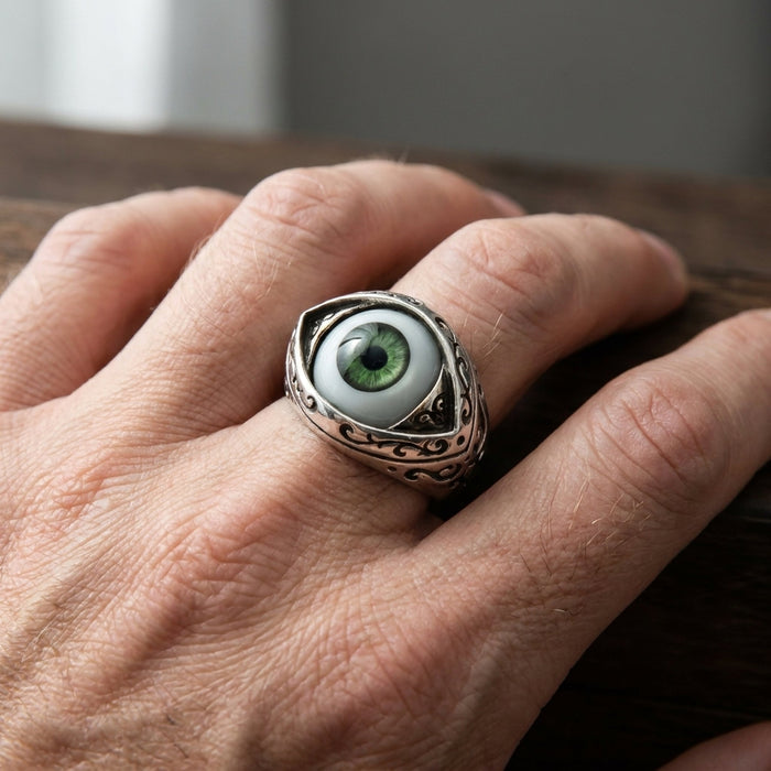 Silver dark green eyeball ring worn on a hand showing the proud-set bezel and Victorian scrollwork shoulders