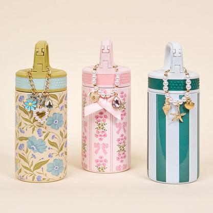 Three tumblers by The Darling Effect feature floral, bow, and striped pastel designs with decorative lids and handles—perfect for displaying your Simply Coquette Tumbler Charm or favorite drinkware accessories.
