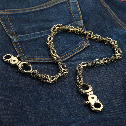Both skull lobster clasps of the brass Dorje wallet chain shown open, one displaying its cross medallion.