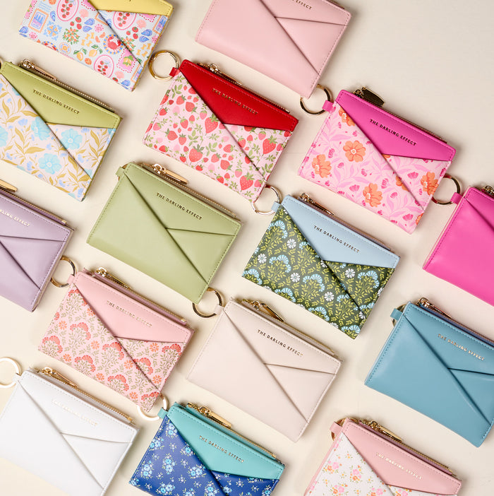 The Darling Effect’s Endless Daydream Cream Luxe Pocket Wallet is a compact vegan leather wallet with an envelope flap, gold zipper, key ring, and a stylish criss-cross design in cream. Perfectly arranged for chic organization.