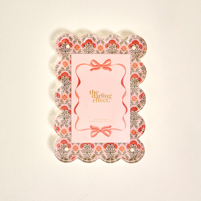 The Darling Effect’s Everbloom Dusty Rose Rectangle Scalloped Acrylic Picture Frame features pink, red, and green floral patterns and a pink center—perfect for anyone who loves stylish, modern frames.