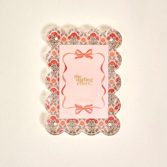 The Darling Effect’s Everbloom Dusty Rose Rectangle Scalloped Acrylic Picture Frame features pink, red, and green floral patterns and a pink center—perfect for anyone who loves stylish, modern frames.
