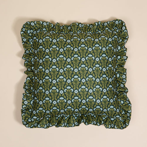 The Darling Effect’s Everbloom Forest Green Scalloped Square Throw Pillow features a floral pattern in light blue and yellow, paired with ruffled edges—a cozy accent layered on a neutral beige background.