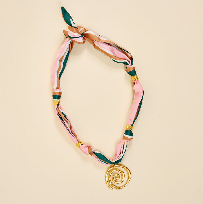 The Darling Effect's Evergreen Twist Make a Statement Scarf Necklace flaunts pink, green, and brown stripes with gold beads and a bold spiral pendant—an artful accessory made to stand out.