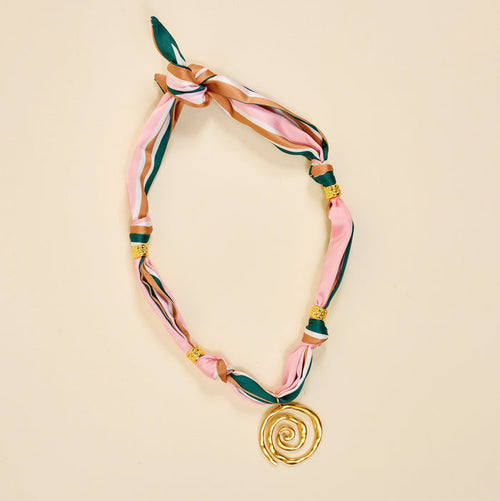 The Darling Effect's Evergreen Twist Make a Statement Scarf Necklace flaunts pink, green, and brown stripes with gold beads and a bold spiral pendant—an artful accessory made to stand out.