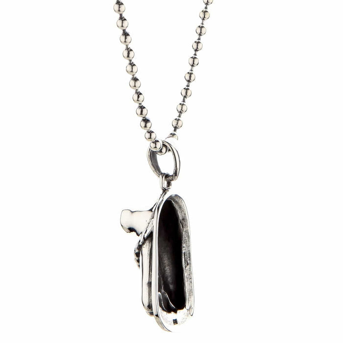 Close-up of a handcrafted sterling silver sandal charm pendant with oxidized details, hanging from a silver ball chain on a white background