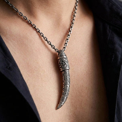 Close-up of a person wearing an intricately engraved sterling silver Ganesh tusk pendant necklace, featuring ornate details and the text 'oriental vibrations', resting on the chest with an open dark shirt.