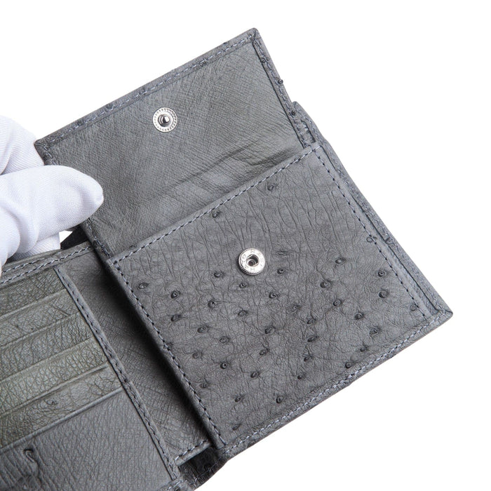 A detail shot of the grey ostrich wallet's interior, with a gloved hand opening the snap-closure coin pocket to show its construction.