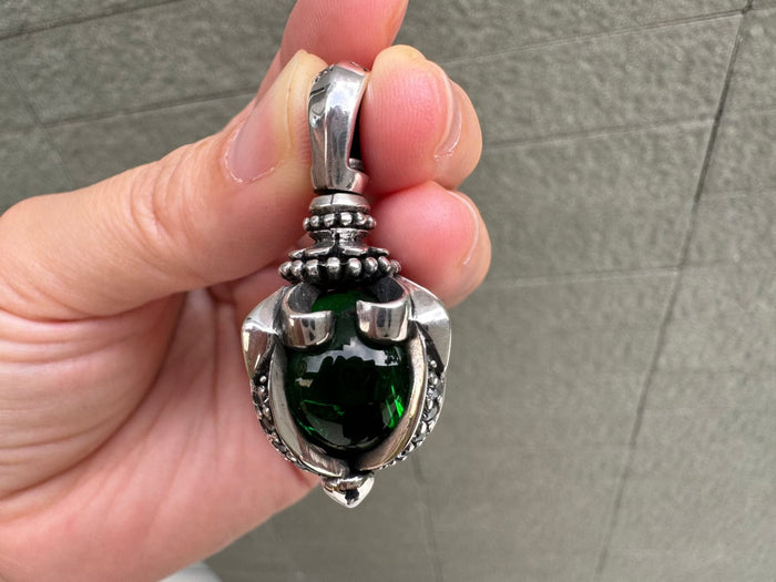 Close-up detailing the thick sterling silver claws and beaded bail securing the dark green moonstone pendant.