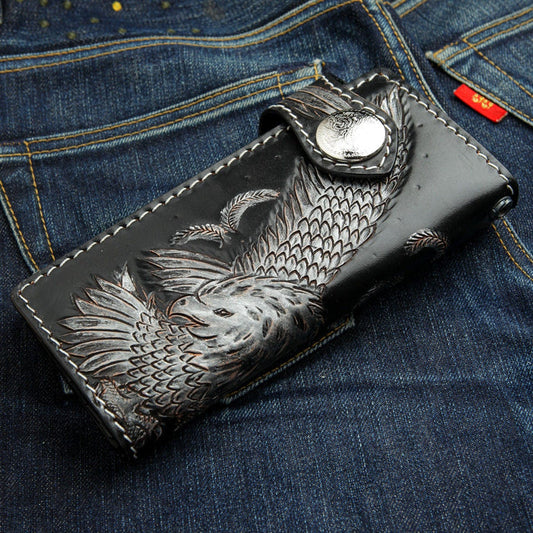 The carved eagle biker wallet with a silver concho snap, resting on blue denim jeans.