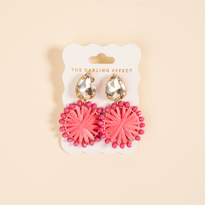 The Darling Effect's Hot Pink Radiant Gem Earrings feature large clear teardrop studs and round pink woven designs with bead accents on a branded card—stylish, lightweight, and perfect for everyday wear.