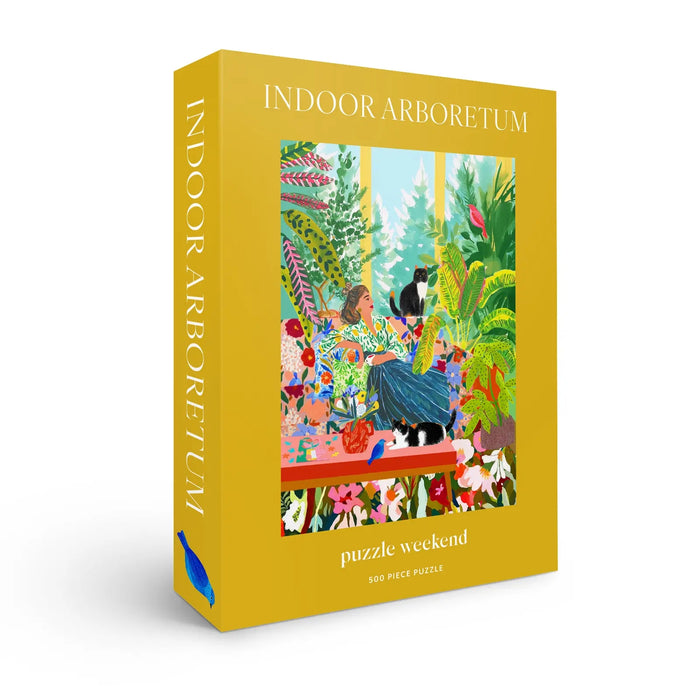 The Puzzle Weekend Indoor Arboretum 500 Piece Jigsaw Puzzle comes in a yellow box and features an illustration of a person and two cats amid lush houseplants.
