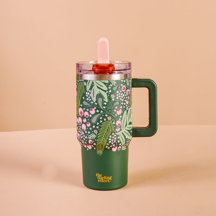 The Darling Effect's Jolly Sprig 20 oz Lifestyle Flip Straw Tumbler is green with pink and white floral designs, green leaves, triple-walled insulation, a clear lid, a pink straw, and "The sassy effect" in yellow at the bottom.