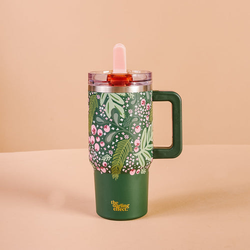 The Darling Effect's Jolly Sprig 20 oz Lifestyle Flip Straw Tumbler is green with pink and white floral designs, green leaves, triple-walled insulation, a clear lid, a pink straw, and "The sassy effect" in yellow at the bottom.