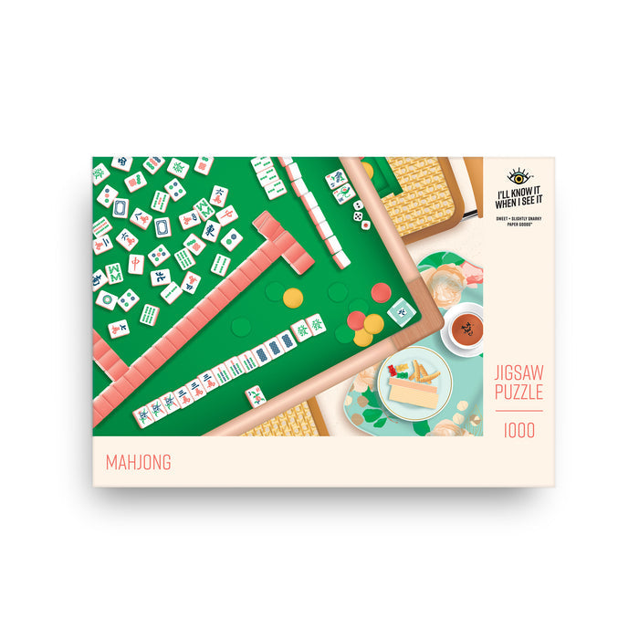The “Mahjong | 1,000 Piece Jigsaw Puzzle” by I’ll Know It When I See It features a Mahjong setup on a green table with snacks and tea. Made from recycled board, the brand and piece count are clearly visible on the box.