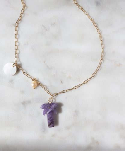 WALD Berlin’s Mexicana Solo Amore Necklace: a handmade gold-plated piece with a white circular charm, yellow bead, and purple hand-carved stone palm pendant, elegantly displayed on white marble.