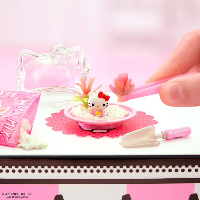 Hello Kitty-themed playset with a hand interacting with it on a pink surface.
