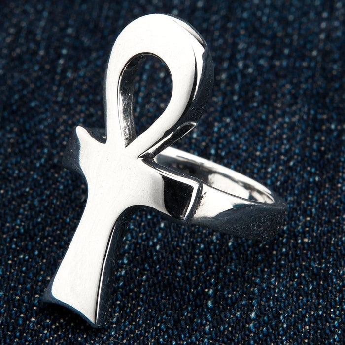 A highly polished sterling silver Ankh ring with a minimalist design, shown on a dark denim background.