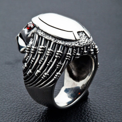 Ribbed tubes run down each side to a pebbled jaw, one red stone set below the smooth oval brow plate.