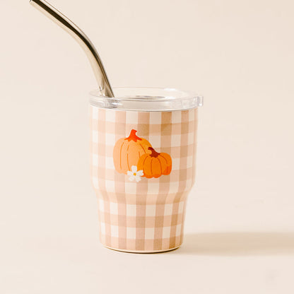 The Darling Effect’s Pumpkin Gingham 2 oz Tiny Tumbler features a beige and white checkered design, clear lid, metal straw, and pumpkin motif—perfect for autumn parties.