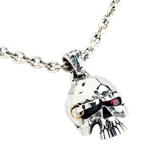 Sterling silver punk skull pendant on a chain, three-quarter view showing the red ruby CZ eye and the brow piercing ring.