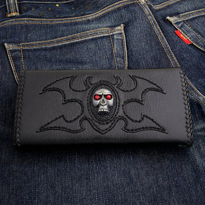 Red eye skull leather trucker wallet — silver-tone skull on a stingray oval with stitched tribal wings, black cowhide
