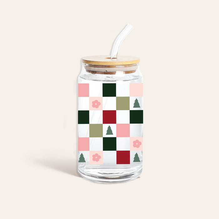 The Darling Effect Round Glass Cup - Holiday Check features clear Libbey glass with a bamboo lid and straw, adorned with a colorful checkered pattern of green, pink, and red squares along with small flowers and tree icons.