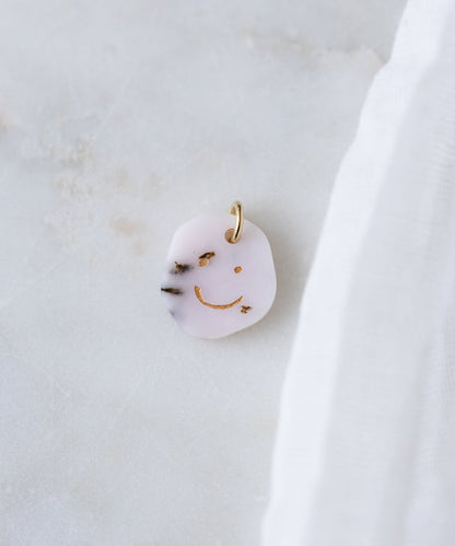 The WALD Berlin Smilie Dude Gemstone Pendant Without Chain features a playful gold smiley face design and is crafted in Germany—perfect as a unique accent for any look.