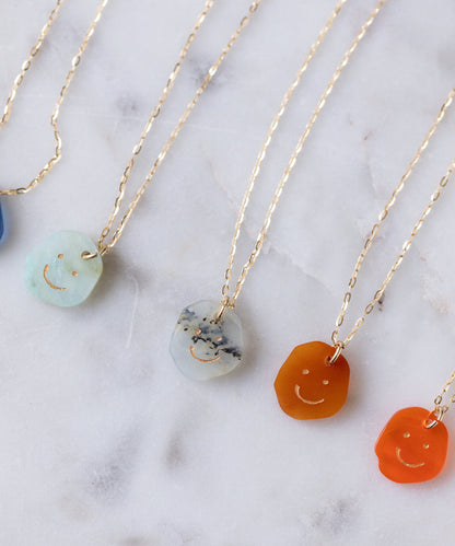 Five Smilie Dude Gemstone Pendants Without Chain by WALD Berlin in various colors with real gemstone accents, shown on a white marble surface.
