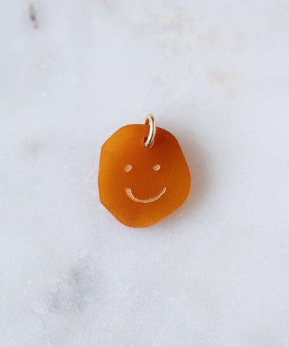 The WALD Berlin Smilie Dude Gemstone Pendant Without Chain is a small, uniquely shaped amber pendant with an engraved smiley face and metal loop—ideal for adding charm to any real gemstone jewelry collection.