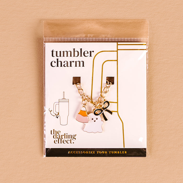 The Darling Effect’s Spooky Sweet Tumbler Charm features a gold chain with candy corn, ghost, and black bow charms—perfect for spooky tumbler flair. Comes carded as a "tumbler charm" on a light tan background.
