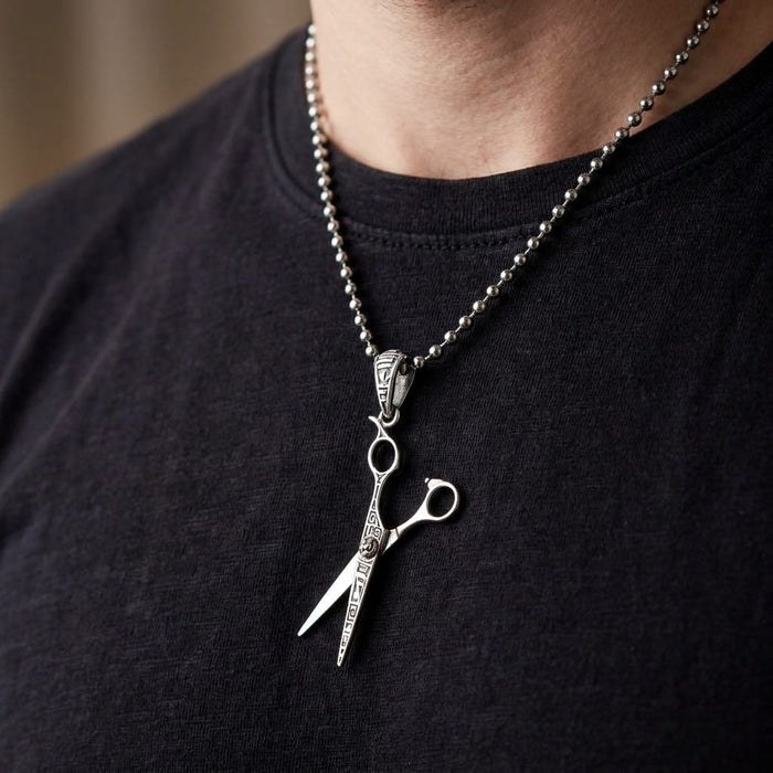 Man wearing a silver scissors pendant on a ball chain necklace.